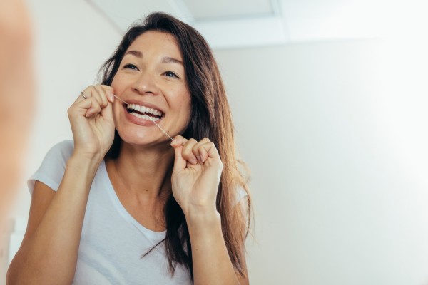Woman flossing her teeth to prevent periodontal disease.